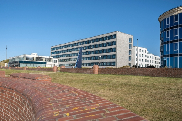 Außenansicht der Klinik Norderney mit einem Kunstwerk von stilisierten Wellen im Vordergrund. Fotografiert von der Seeseite. Außenansicht der Klinik Norderney mit einem Kunstwerk von stilisierten Wellen im Vordergrund. Fotografiert von der Seeseite.