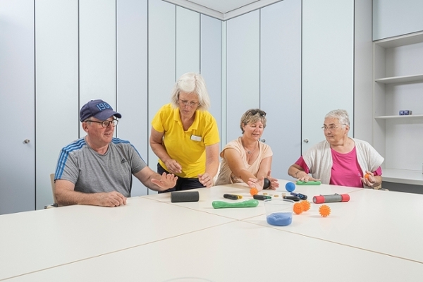 Zwei Patientinnen und ein Patient werden von einer Therapeutin geschult. Zwei Patientinnen und ein Patient werden von einer Therapeutin geschult.