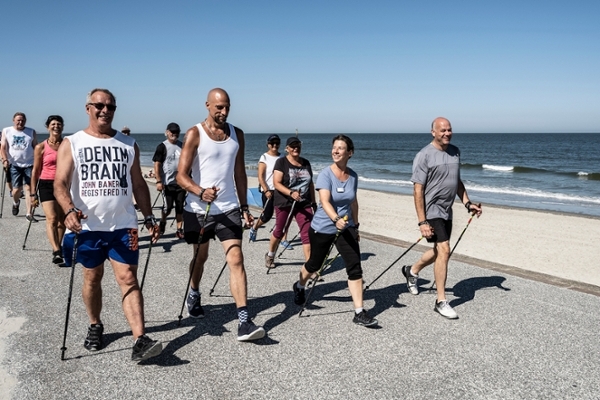 Eine Gruppe von Patientinnen und Patienten der Klinik Norderney walkt am Strand Eine Gruppe von Patientinnen und Patienten der Klinik Norderney walkt am Strand