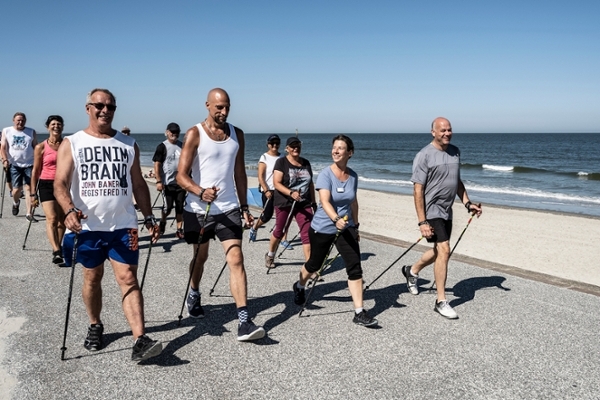 Eine Gruppe von Patientinnen und Patienten der Klinik Norderney walkt am Strand